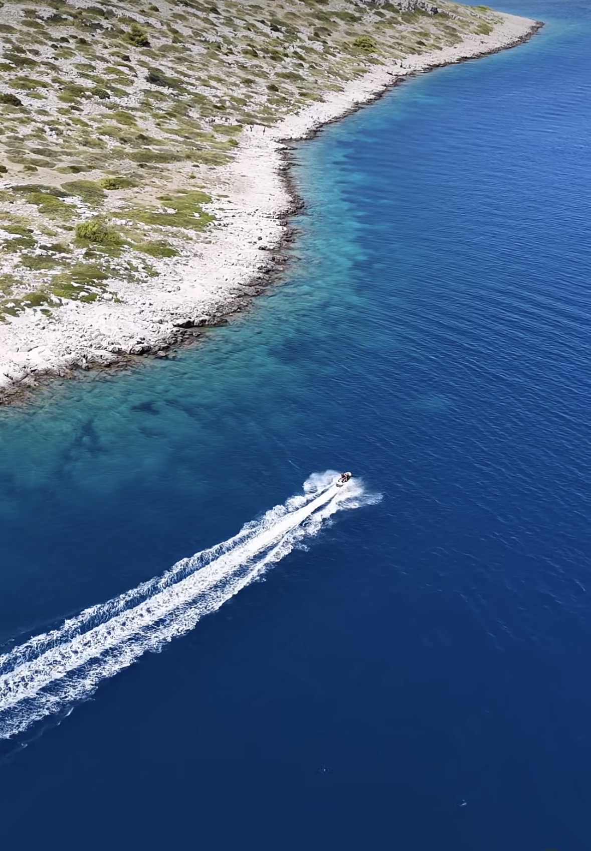 Boat crossing deep blue water beside the rocky Kornati islands